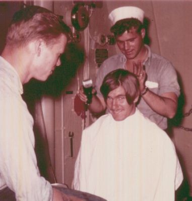 This is a picture of "yours truely" getting a well needed haircut!  
It's amazing how much hair you can get under a whitehat during inspection 
if you have the right barber!  
I suppose Chasteen would've shaved it all off!   
That's why we cut each others I'm sure!  
Our barber is none other than Leroy McCall, doing a fine job here.  
He looks like he's having fun, while Ken Johnson looks on.   
Where are these guys today?  
I heard that McCall went back in the Navy after being discharged on the Semmes.

Mitch

