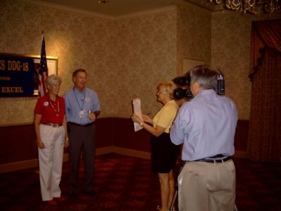 Tracy & Ted McCourtney recording for video of reunion, Bonnie Beinhaur holding 
Q card.
